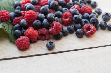 Orman meyveleri - Ahşap zemin üzerinde ahududu ve yaban mersini