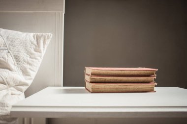 Yatağın yanındaki retro beyaz masa üzerine kitaplar İskandinav iç tarafsız renk paleti.