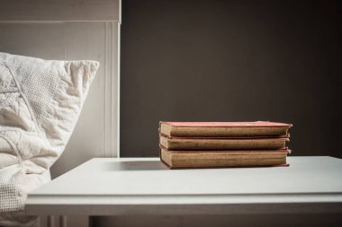 Yatağın yanındaki retro beyaz masa üzerine kitaplar İskandinav iç tarafsız renk paleti.