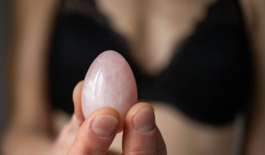 Elinde vajina yumurtası tutan bir kadın. Gül kuvars kristal yeşim yumurta. 