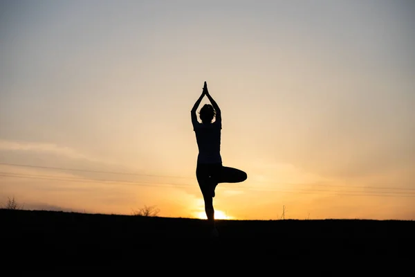 Gün Batımında Denge Pozisyonunda Olan Bir Kadın Dışarıda Yoga Yapıyor — Stok fotoğraf