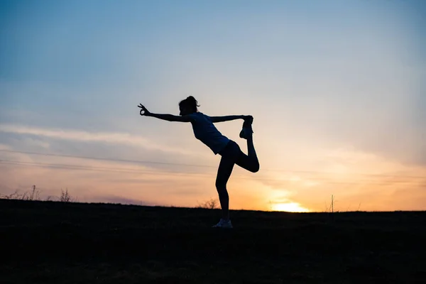 woman in a balancing pose at sunset yoga outdoors