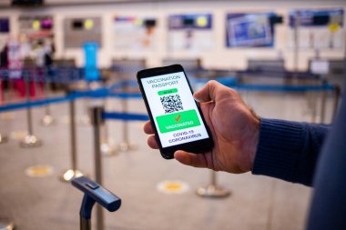 Coronavirus veya Covid-19 için sağlık aşısı pasaportu. Havaalanında Uluslararası Sertifikalı Seyahat İçin Bağışıklık Statüsünde Aşıyla Gezgin Cep Telefonu Kullanıyor