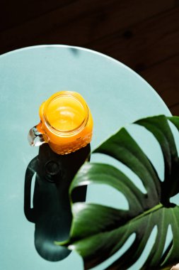 Yaz ışığında taze portakal suyu ve canavar ya da ayrık yapraklı filodendron yaprakları