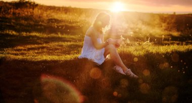 Kadın gün batımında dışarıda oturuyor. 