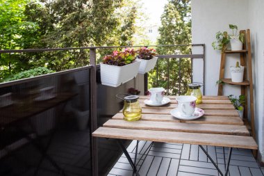 Yazın çiçekli ve kahve masalı küçük bir apartman terası.