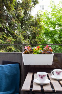 Yazın çiçekli ve kahve masalı küçük bir apartman terası.