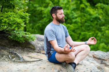Genç adam dışarıda meditasyon yapıyor. 