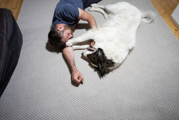 man on the floor hugging his dog