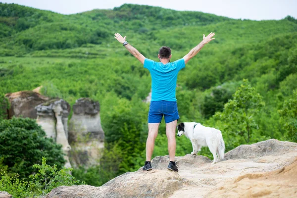 男人和他的狗坐在岩石上享受大自然 — 图库照片