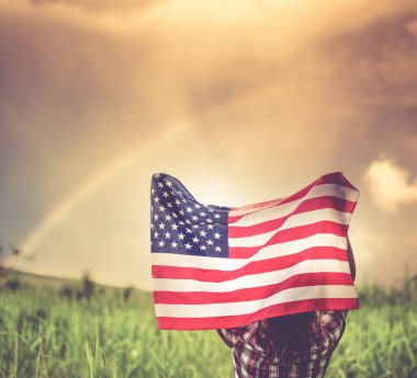 Amerikan bayrağını gökkuşağının bağımsızlık gününe karşı tutan kadın