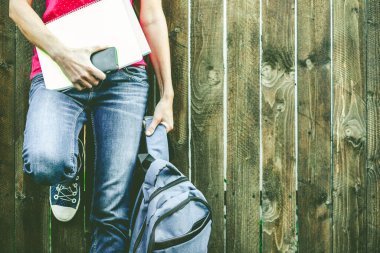 Sırt çantalı, kot pantolonlu kız bacakları okula geri döndü.