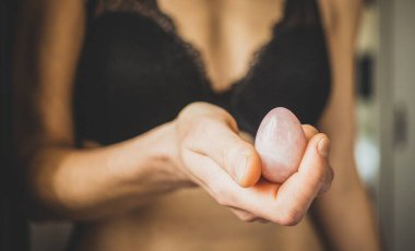 Elinde vajina yumurtası tutan bir kadın. Gül kuvars kristal yeşim yumurta.