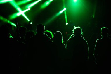 Konserdeki kalabalık ve sahne ışıklarındaki siluetler