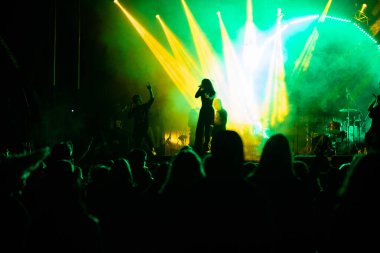 Konserdeki kalabalık ve sahne ışıklarındaki siluetler