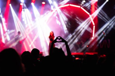 Konserdeki kalabalık ve sahne ışıklarındaki siluetler