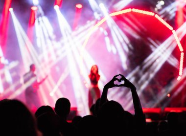 Konserdeki kalabalık ve sahne ışıklarındaki siluetler