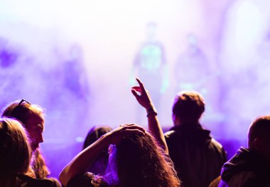 Konserdeki kalabalık ve sahne ışıklarındaki siluetler