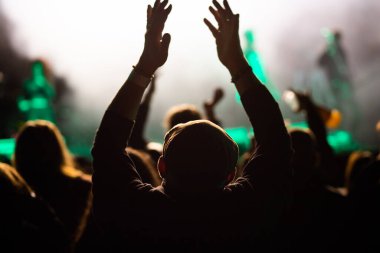 Konserdeki kalabalık ve sahne ışıklarındaki siluetler