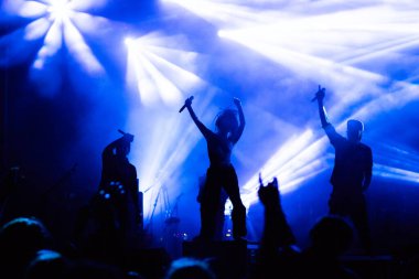 Konserdeki kalabalık ve sahne ışıklarındaki siluetler