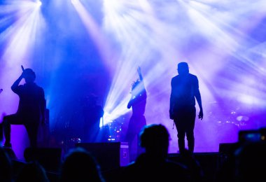 Konserdeki kalabalık ve sahne ışıklarındaki siluetler