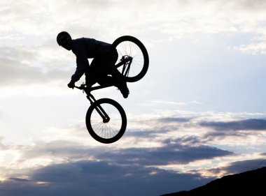 bmx bisiklet ile bir sıçrama yapan bir erkek silüeti 