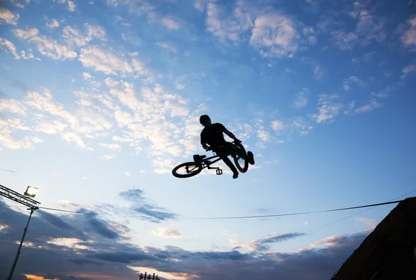 Silueta de un hombre haciendo un salto con una bicicleta bmx — Foto de Stock