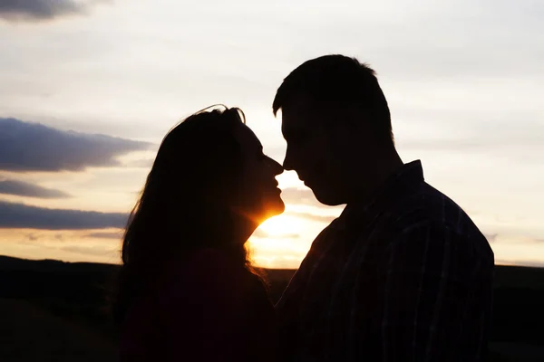 Silhouette of loving couple holding hands in heart shape over or — Stock Photo, Image