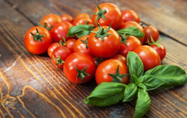 Kiraz domates ve fesleğen ahşap arka plan üzerinde 