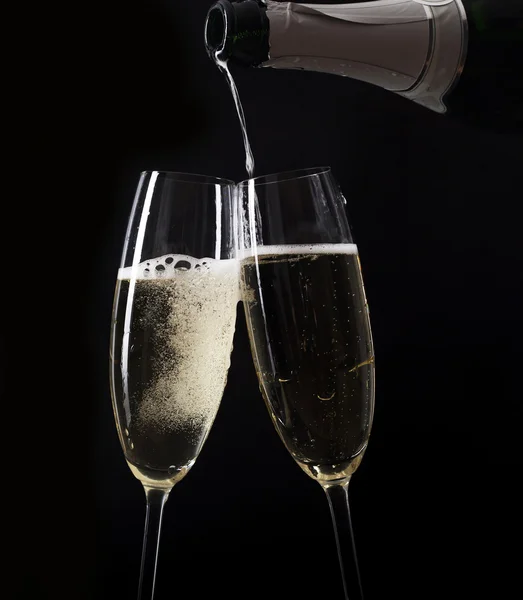 Champanhe derramando em dois copos de uma garrafa — Fotografia de Stock