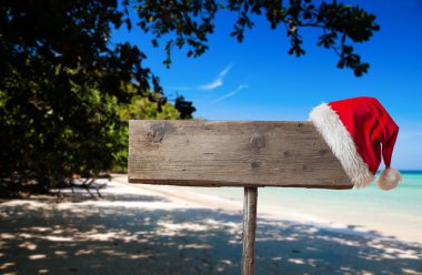Tropik sahilde Noel şapka ile ahşap tabela 