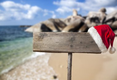 Tropik sahilde Noel şapka ile ahşap tabela 
