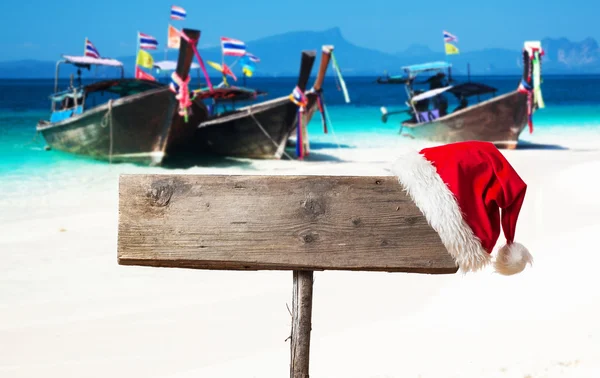 Houten bord met kerst hoed op tropisch strand — Stockfoto