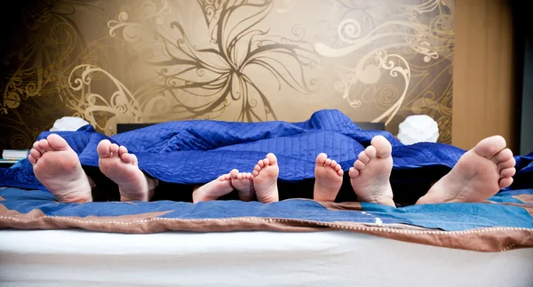 Quatro pares de pernas da família feliz na cama - pai, mãe a — Fotografia de Stock