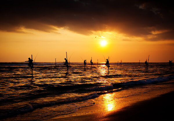 Silhouettes of the traditional stilt fishermen at the sunset nea