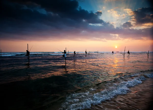 Silhouette dei tradizionali pescatori di trampoli al tramonto nea — Foto Stock