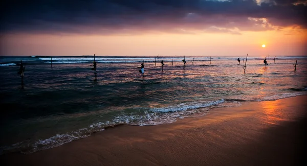 Silhouettes of the traditional stilt fishermen at the sunset nea — Stock Photo, Image