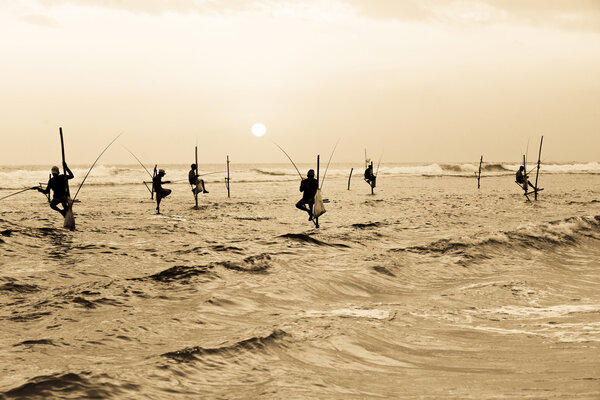 Silhouettes of the traditional stilt fishermen at the sunset nea