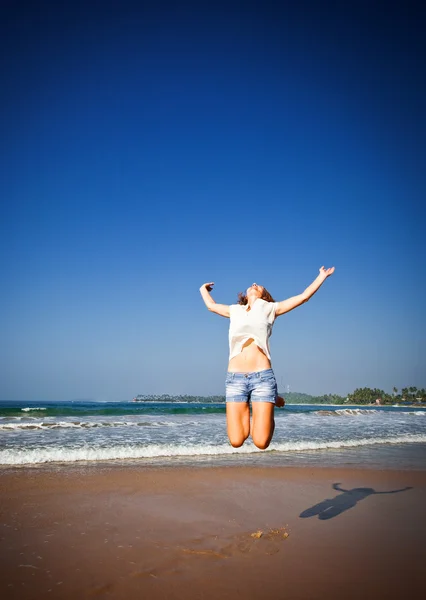 Femme sautant dans les airs sur la plage tropicale — Photo