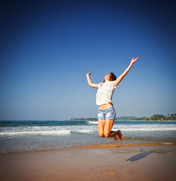 Femme sautant dans les airs sur la plage tropicale — Photo