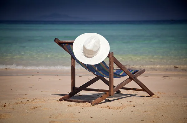 Exotic beach holiday background with white hate on beach chair — Stock Photo, Image