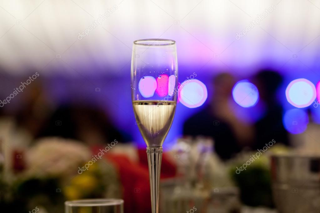 Glass with champagne lit by nightclub lights