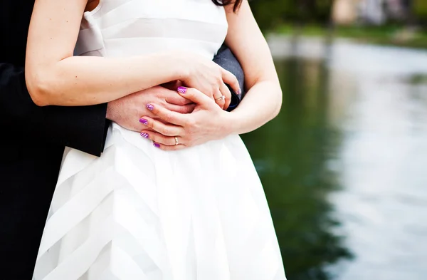 Pasangan yang baru menikah merangkul - fokus pada tangan dengan cincin kawin — Stok Foto