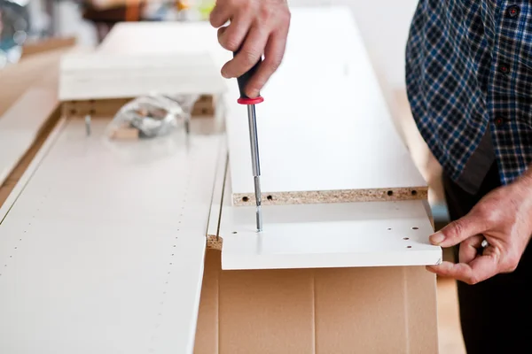 Hombre montando muebles de paquete plano —  Fotos de Stock