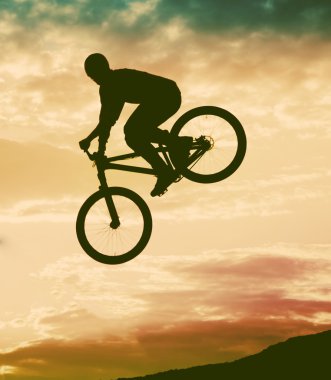 Günbatımı karşı bir bmx bisiklet ile bir sıçrama yapan bir erkek silüeti 