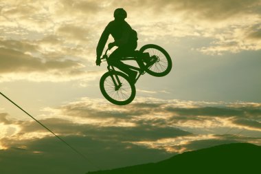 Günbatımı karşı bir bmx bisiklet ile bir sıçrama yapan bir erkek silüeti 