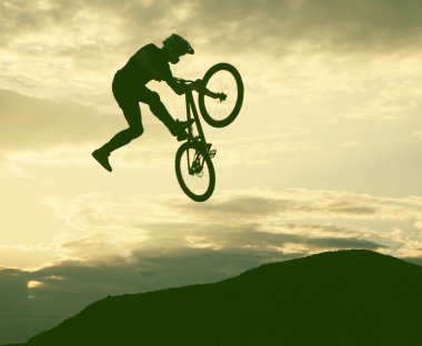 Günbatımı karşı bir bmx bisiklet ile bir sıçrama yapan bir erkek silüeti 