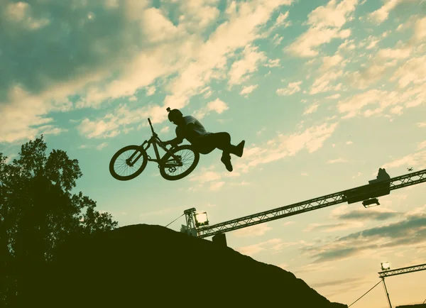 Silueta de un hombre haciendo un salto con una bicicleta bmx contra el atardecer — Foto de Stock