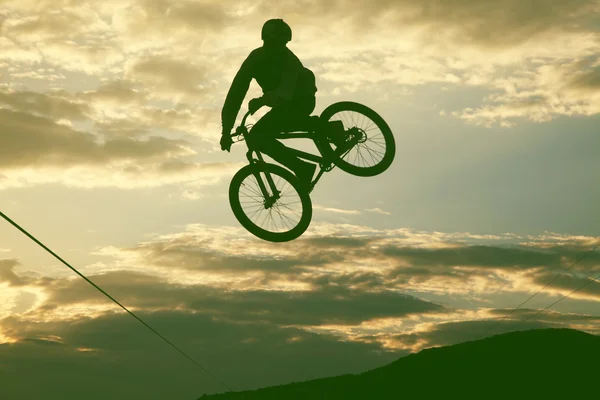 Silhouette d'un homme faisant un saut avec un vélo bmx contre le coucher du soleil — Photo