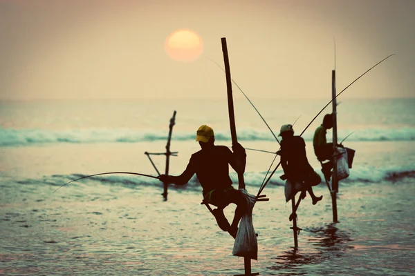 Silhouetten der traditionellen Stelzenfischer bei Sonnenuntergang in der Nähe der Insel — Stockfoto